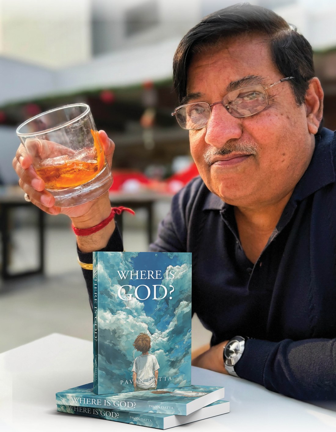 Author Pavan Datta raising a glass beside stacked copies of his novel Where Is God? at the book launch
